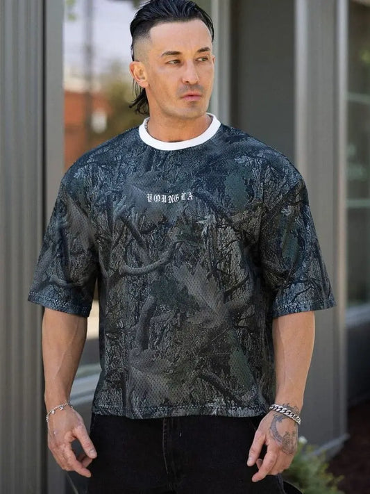 Man wearing a black oversized graphic tee standing indoors.