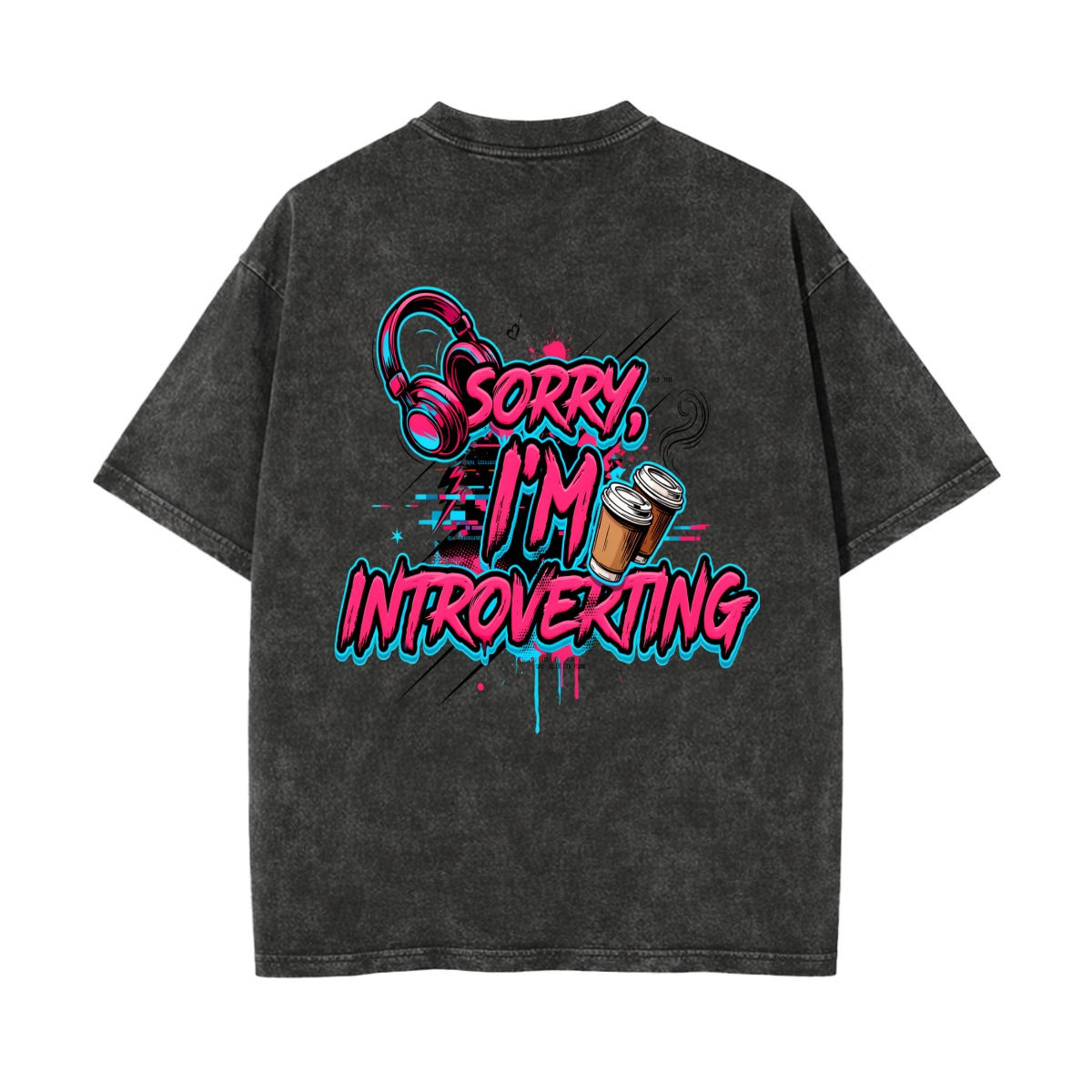 A dark gray acid-wash t-shirt shown from the back, featuring a colorful graphic print with the text 'SORRY, I'M INTROVERTING' in pink and blue graffiti-style lettering, accompanied by headphones and a coffee cup illustration.