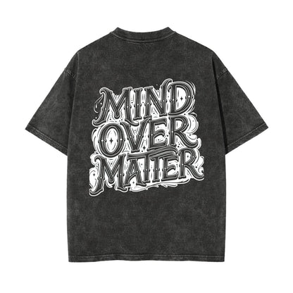 A washed black short-sleeve t-shirt with a large white graphic text print reading 'MIND OVER MATTER' on the back, shown against a plain white background.