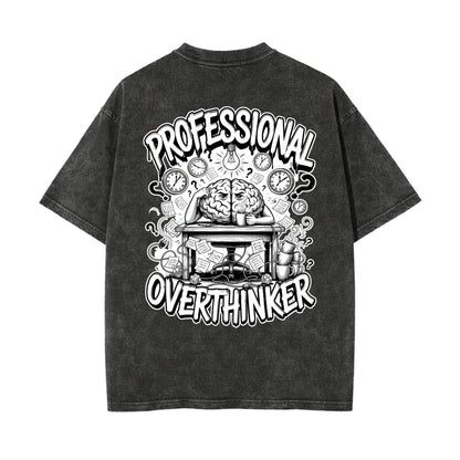 A dark gray acid-wash t-shirt shown from the back, featuring a large black and white graphic print with the words 'PROFESSIONAL OVERTHINKER' and an illustration of a brain working at a desk surrounded by clocks.