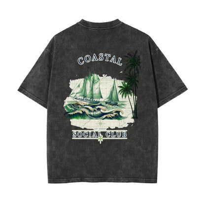 A dark gray acid-wash t-shirt shown from the back, featuring a graphic print of sailboats on waves, palm trees, and the text 'COASTAL SOCIAL CLUB'.