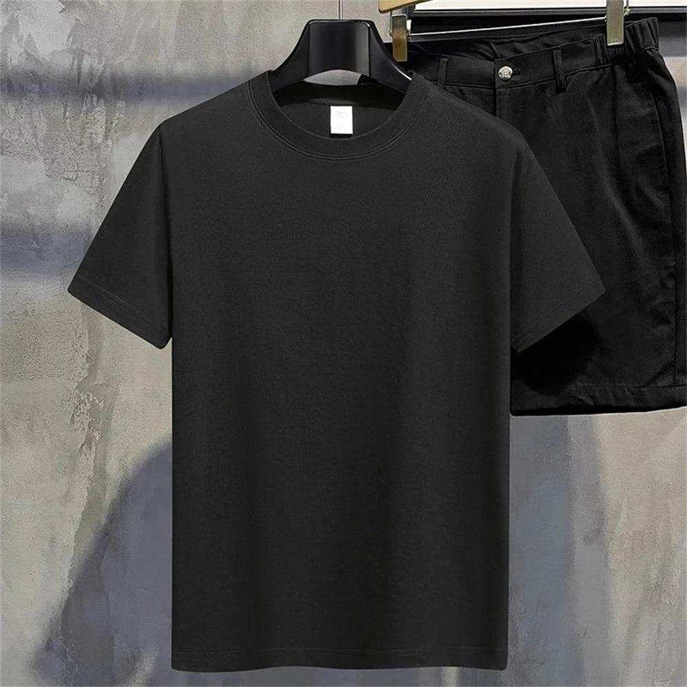 Black full plain t shirt and black pants on hangers against a neutral background