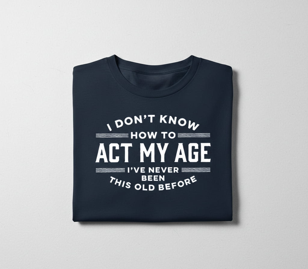 Folded navy blue sarcastic aging humor tee with white text on a light gray background