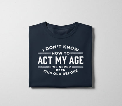 Folded navy blue sarcastic aging humor tee with white text on a light gray background