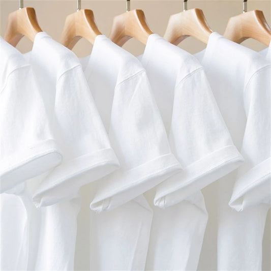 Multiple white plain shirts on wooden hangers against a neutral background