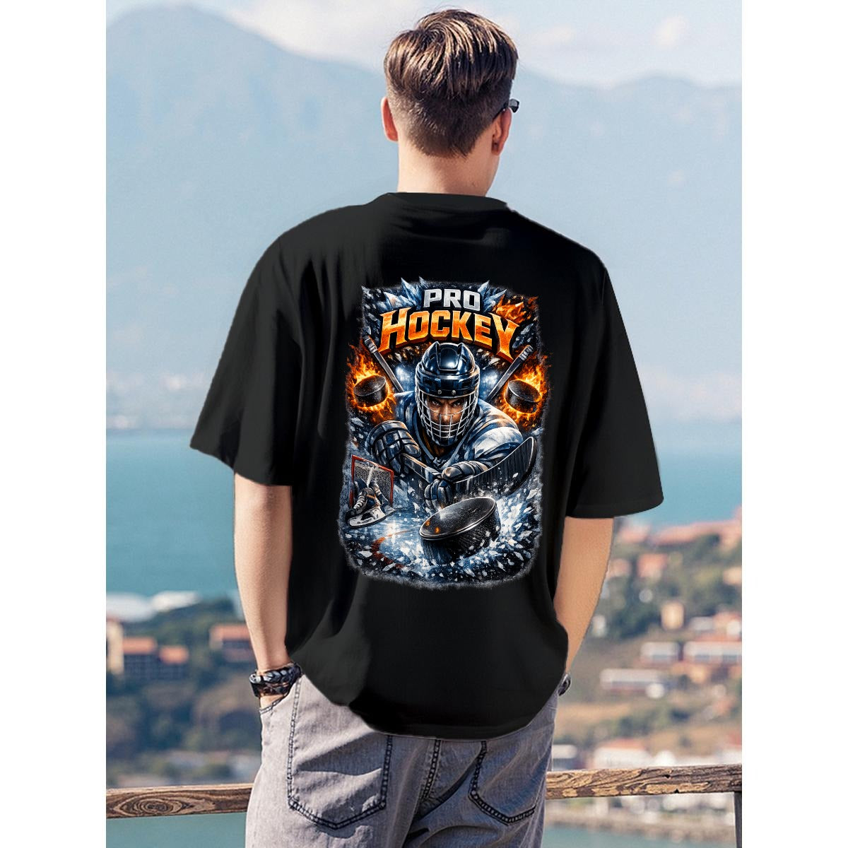 A man viewed from behind wearing a black short-sleeve t-shirt with a large graphic print on the back featuring a hockey player and the words 'PRO HOCKEY'. The background shows a scenic outdoor view of a lake and mountains.