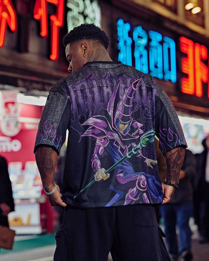 Person wearing a black and purple oversized anime t shirt for men with a mystical sorcerer anime design, standing in front of neon signs.