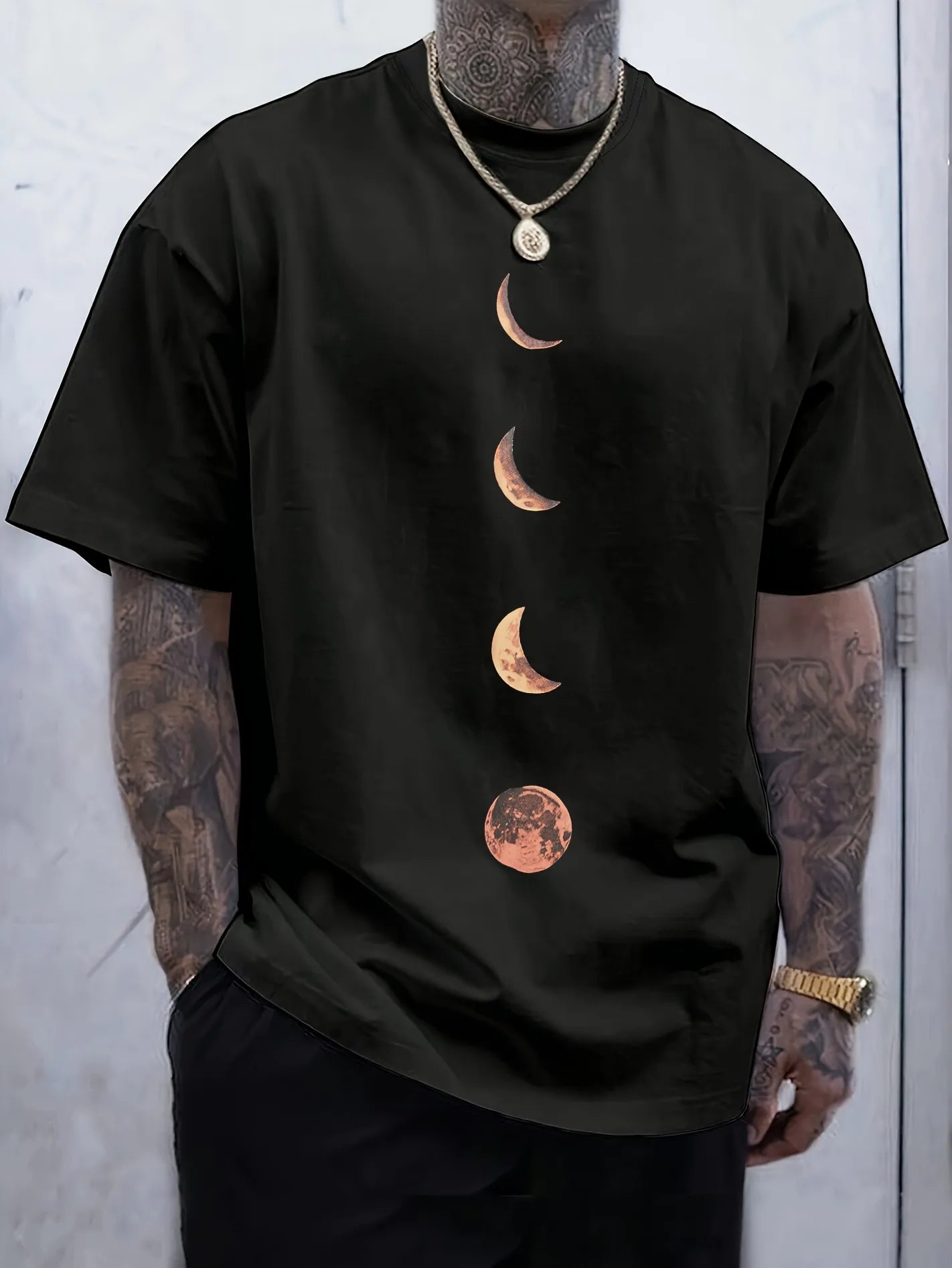 Person wearing a black moon tee with moon phase design against a light gray background