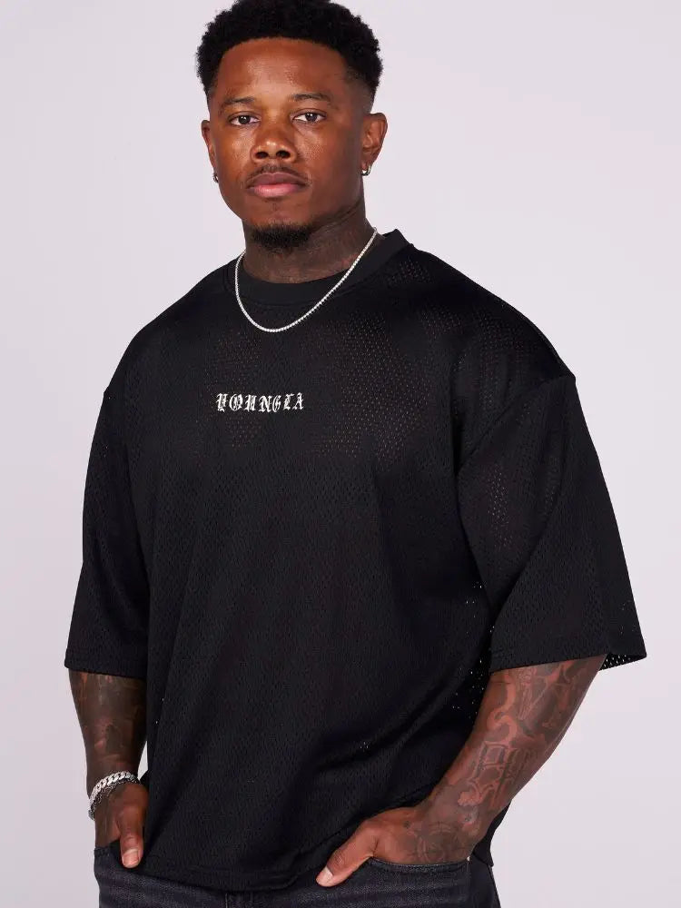 Man wearing a black oversized graphic tee on a plain background