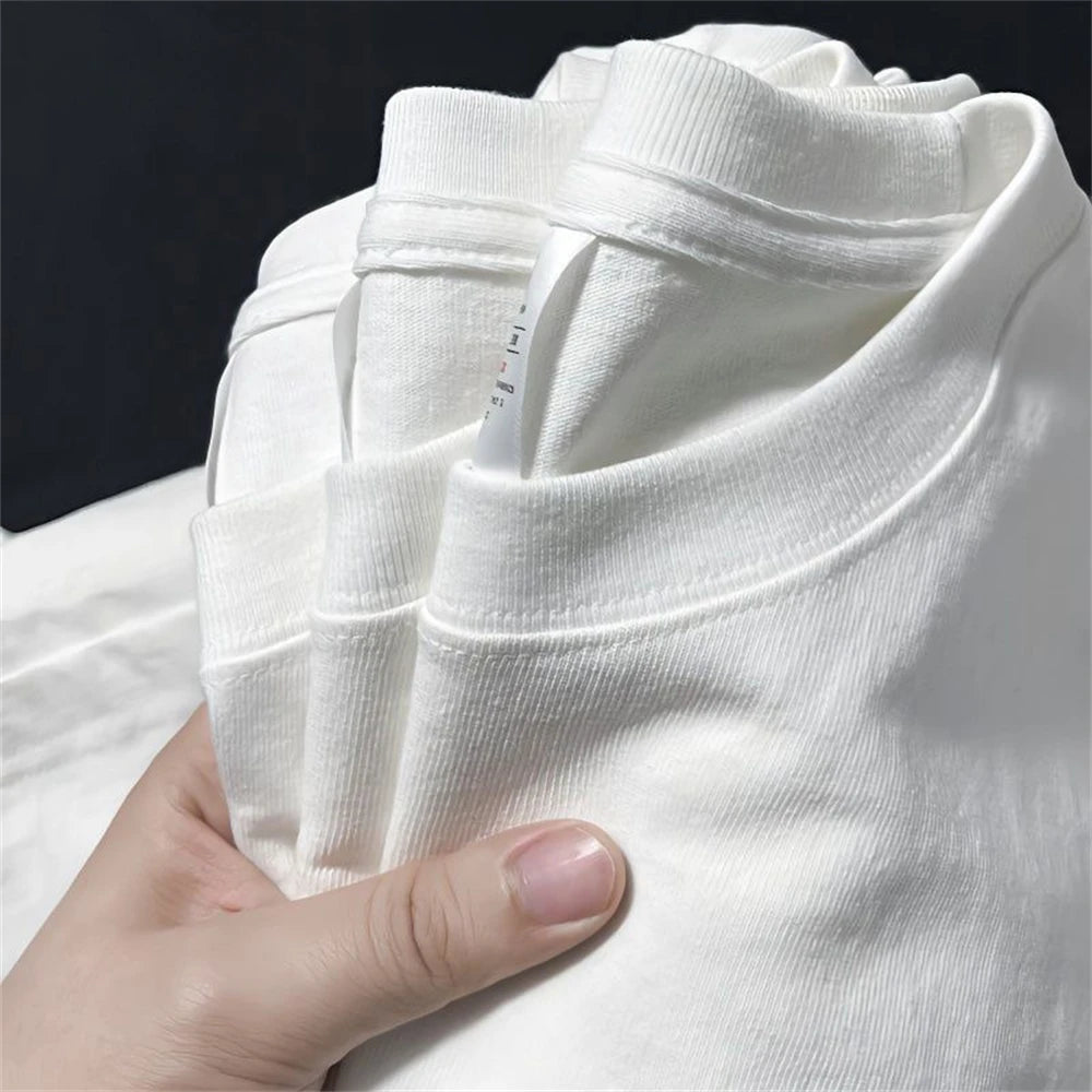 Stack of full white plan t shirts held by a hand against a dark background