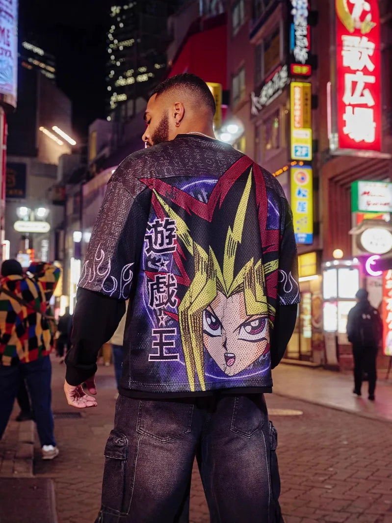 Person wearing a colorful oversized anime cartoon t shit for men on a neon-lit street at night.