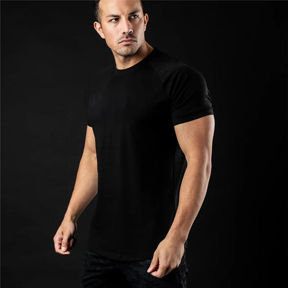 Man wearing a plain black t shirt against a black background