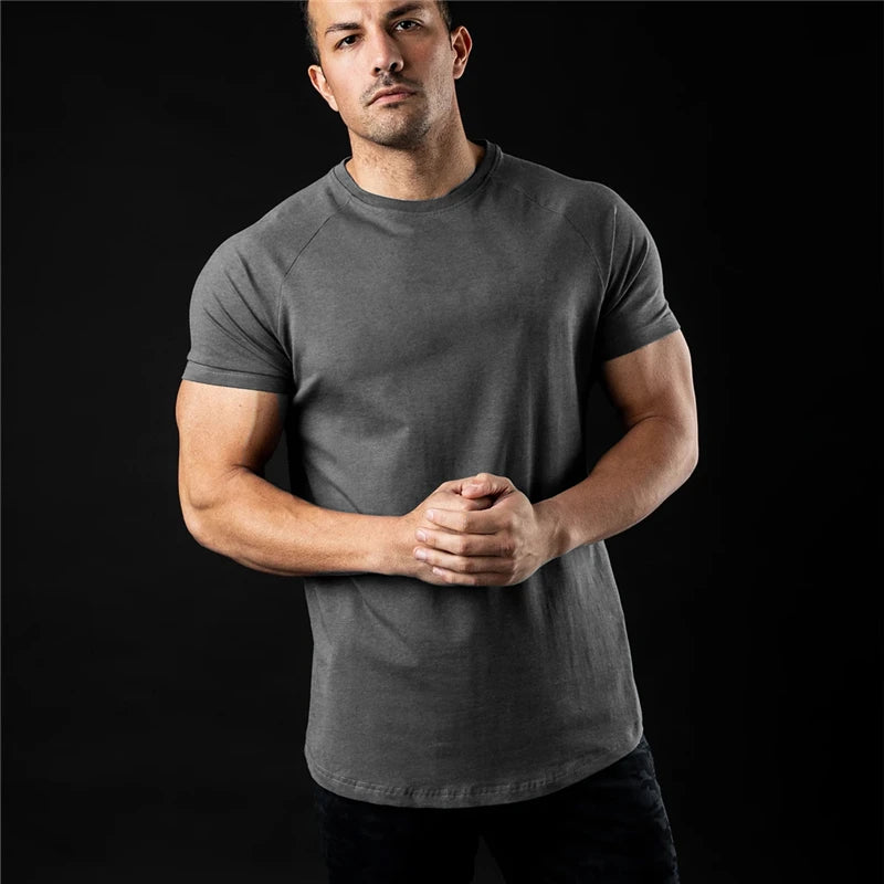 Man wearing a plain dark grey t shirt against a black background